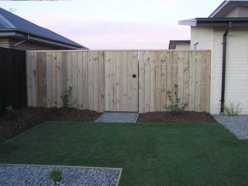 Timber paling fence with a pair of solid timber gates across a side entrance