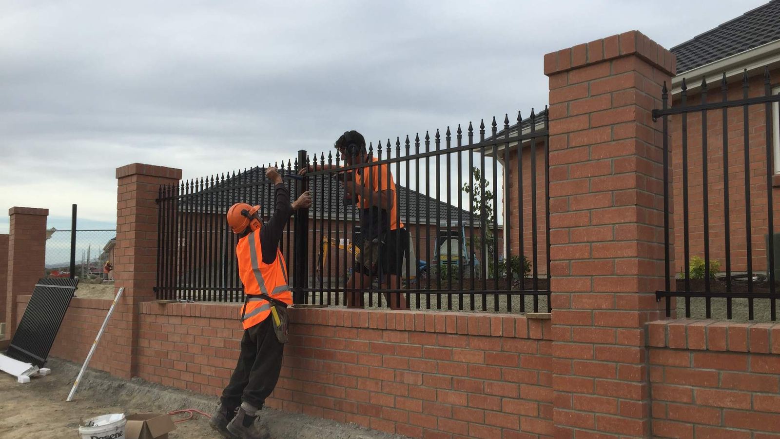Black powder coated steel fence panels set between brick piers