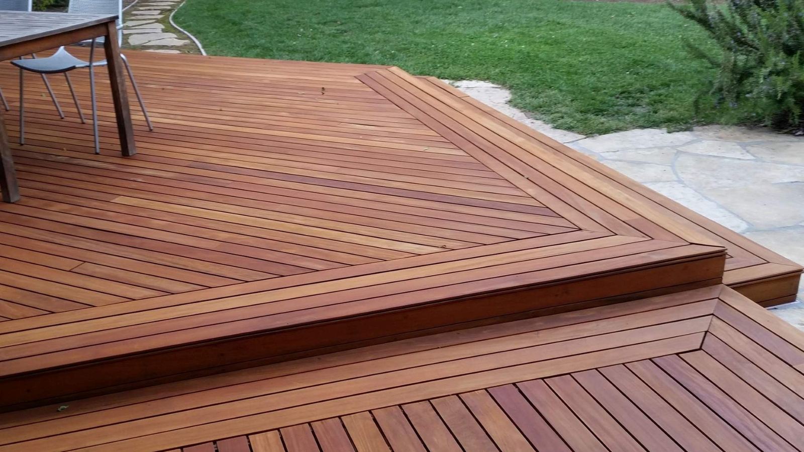 Hardwood timber deck with mitred edge boards beside a lawn