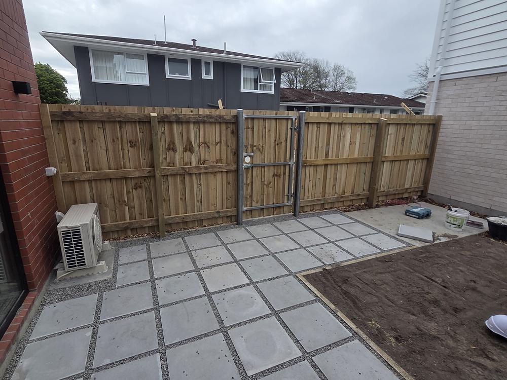 Timber paling fence and a galvanised steel pedestrian gate around a newly paved courtyard